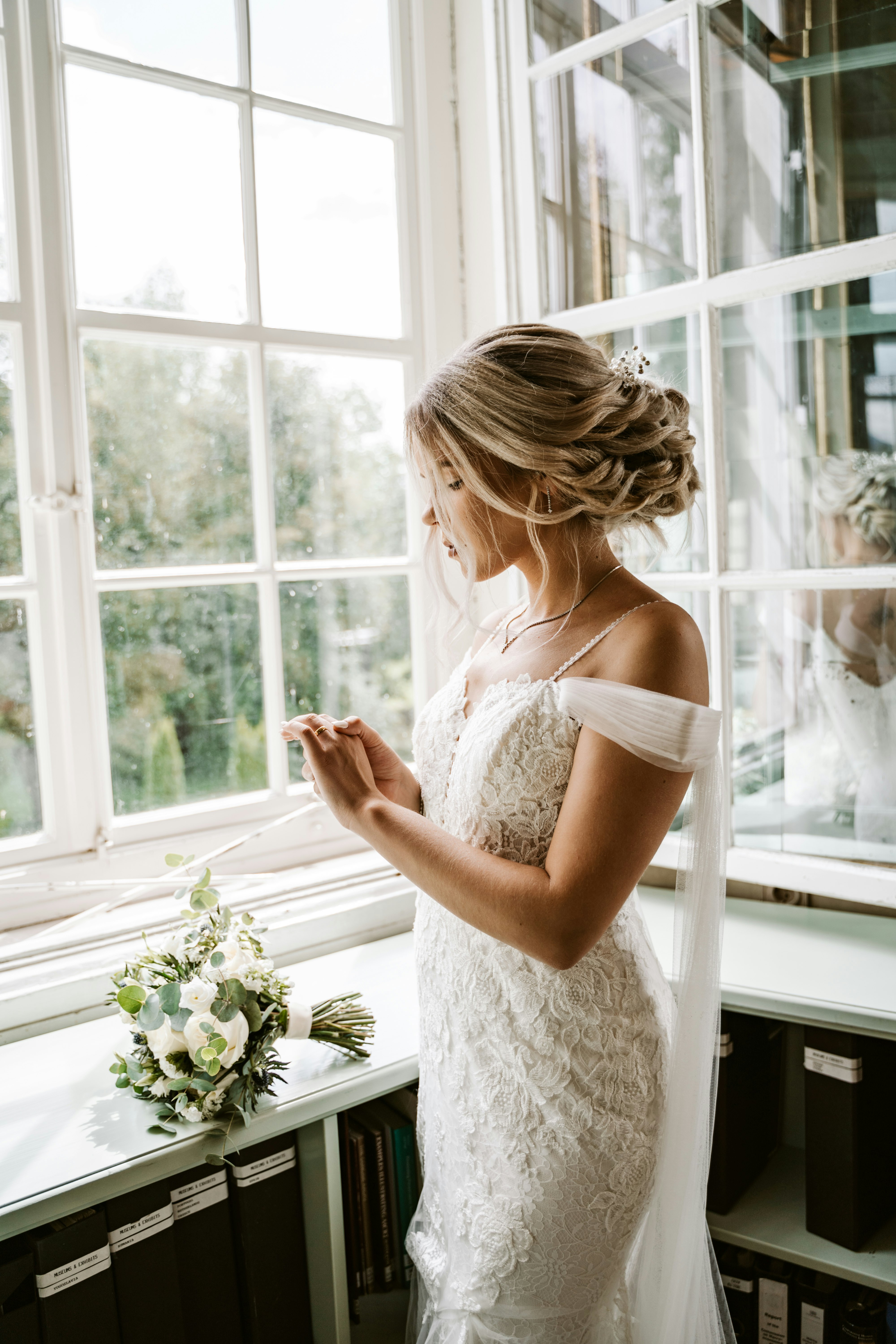woman in white lace sleeveless dress standing near window